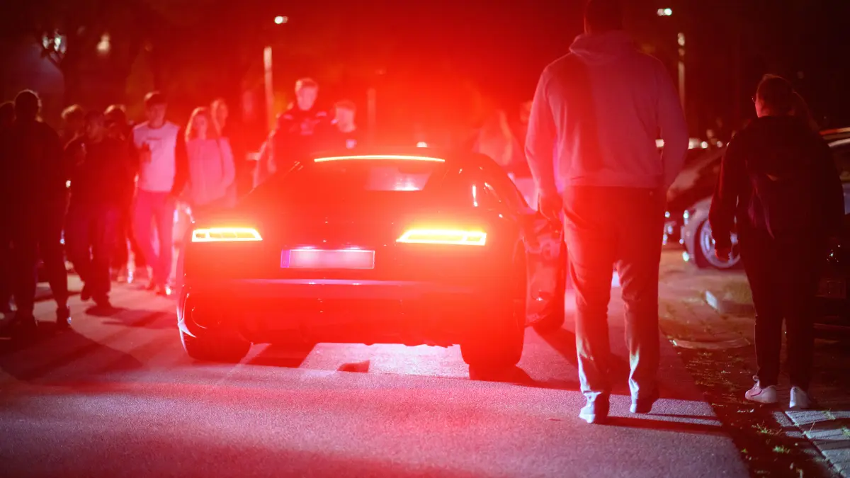 Interessierte laufen zwischen getunten Fahrzeugen am Expo-Park. Erneut haben sich am Freitagabend auf dem ehemaligen Expo-Gelände in Hannover hunderte Auto-Tuner und Autofans getroffen. Die Polizei Hannover kontrollierte an den Zufahrtsstraßen zahlreiche Fahrzeuge. (ACHTUNG: Kennzeichen wurde unkenntlich gemacht!) +++ dpa-Bildfunk +++ Poser