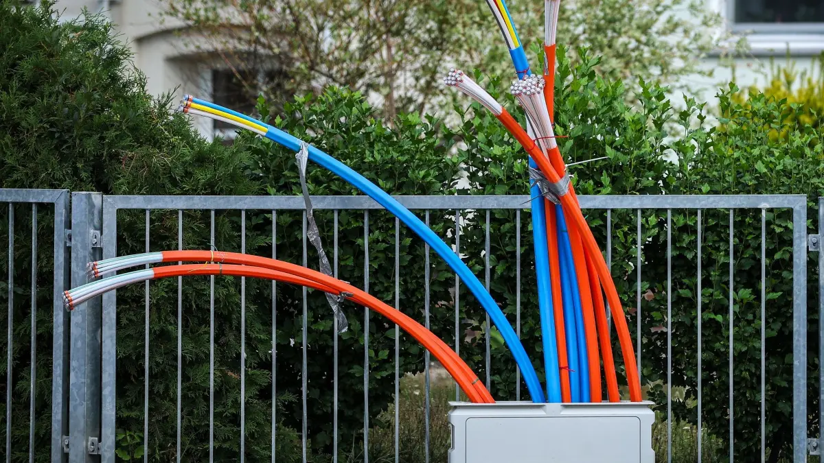 Glasfaserausbau: ARCHIV - 26.07.2023, Sachsen, Zwenkau: Aus dem Sockel eines Schaltschranks ragen Glasfaserkabel heraus. Der ostdeutsche Glasfasernetzbetreiber Envia Tel forciert aktuell in 26 Kommunen den Ausbau von schnellem Internet via Glasfaser für 53.500 Haushalte - vor allem im Erzgebirge. (zu dpa: «Envia Tel forciert Glasfaserausbau in Kommunen») Foto: Jan Woitas/dpa +++ dpa-Bildfunk +++