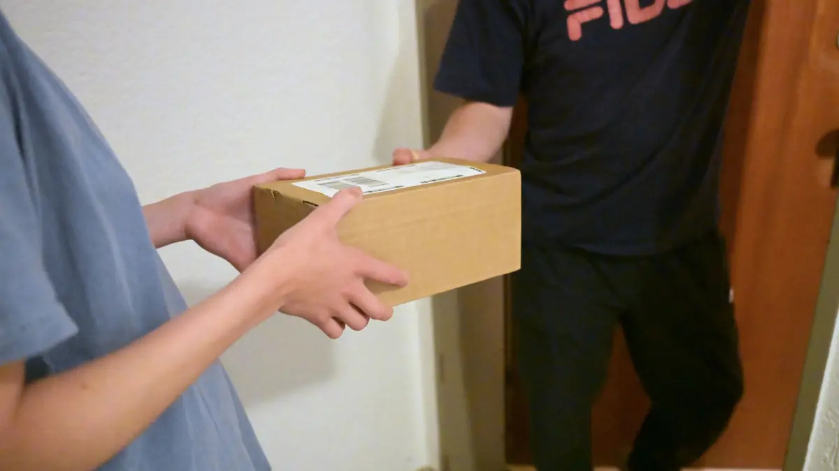 Vor dem Tag der Nachbarn: PRODUKTION - 19.05.2026, Bayern, München: In einem Hausflur übergibt ein Bewohner ein abgegebenes Paket an einen Nachbarn (nachgestellte Szene). Nachbarn nehmen Paketsendungen häufig gegenseitig an, wenn Empfänger nicht zuhause sind. (zu dpa: «Dein Nachbar, das unbekannte Wesen») Foto: Malin Wunderlich/dpa +++ dpa-Bildfunk +++