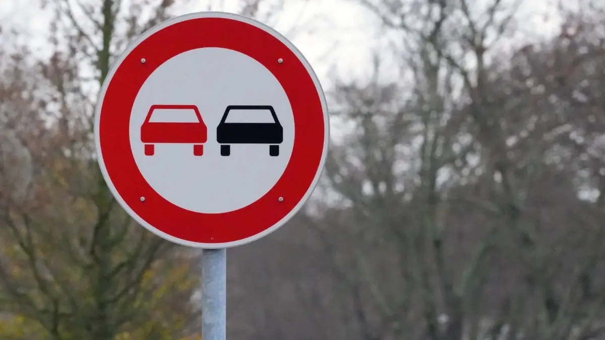 Überholverbot: PRODUKTION - 21.11.2023, Brandenburg, Dahlewitz: Ein Verkehrsschild mit einem stilisierten roten und schwarzen PKW zeigt am Straßenrand das Überholverbot für Fahrzeuge aller Art an. (zu dpa: «Frontalcrash nach riskantem Überholmanöver endet glimpflich») Foto: Soeren Stache/dpa +++ dpa-Bildfunk +++