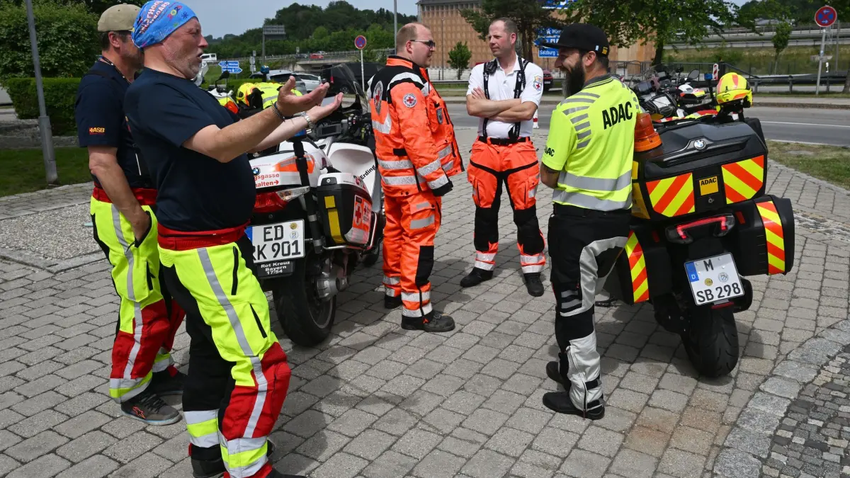 Demo auf Brennerautobahn - Deutschland: 30.05.2026, Bayern, Irschenberg: ADAC-Stauberater und Mitarbeiter des Deutschen Roten Kreuzes stehen auf der Raststätte Irschenberg an der A8 für eine Lagebesprechung zusammen. Die Brennerautobahn in Tirol, Österreich, ist für eine Anwohner-Demonstration für mehrere Stunden gesperrt. Die Anwohner protestieren gegen die seit Jahren wachsende Verkehrsflut. Foto: Felix Hörhager/dpa +++ dpa-Bildfunk +++