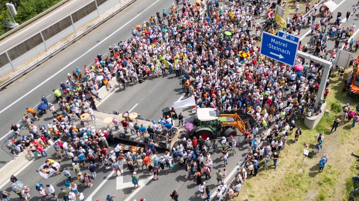 Demonstration und Totalsperre auf Brennerautobahn: 30.05.2026, Österreich, Matrei Am Brenner: Zahlreiche Menschen demonstrieren auf der gesperrten Brennerautobahn. Wegen einer Demonstration auf der Brennerautobahn ist die wichtigste Verkehrsverbindung zwischen Deutschland und Italien in beide Richtungen nahezu vollständig blockiert. (Luftaufnahme mit einer Drohne) Foto: Peter Kneffel/dpa +++ dpa-Bildfunk +++