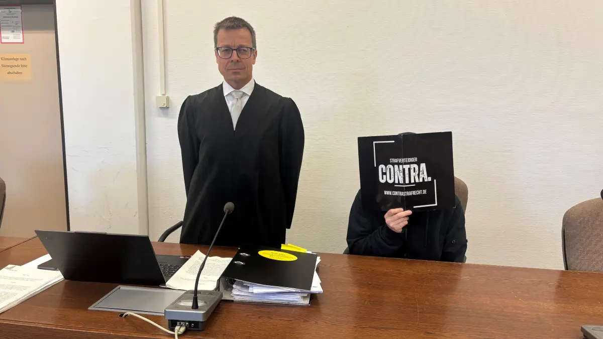 Achim Lippoth verbirgt sein Gesicht hinter einer Kladde, links von ihm sein Verteidiger, Professor Holm Putzke.