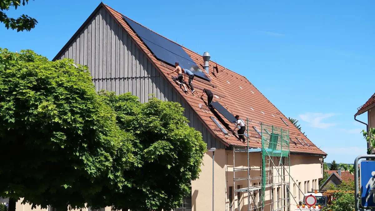 Arbeiter montieren auf dem Dach der Bibliothek im Kronenhof die mittlerweile 11. PV-Anlage der Gemeinde.