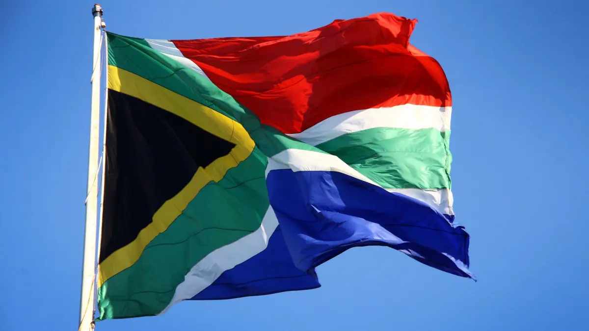 Südafrika: ARCHIV - 22.08.2013, Südafrika, Port Elizabeth: Eine südafrikanische Flagge weht in Port Elizabeth, Südafrika. In der Nähe der Wirtschaftsmetropole Johannesburg wurden bei einer Massenschießerei mindestens 12 Menschen getötet und neun weitere verletzt. (zu dpa: «Bewaffnete in Südafrika fallen in Siedlung ein - zwölf Tote») Foto: Steffen Trumpf/dpa +++ dpa-Bildfunk +++