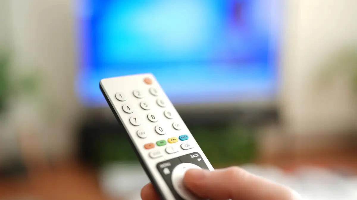 Ein Mann drückt einen Knopf auf einer TV-Fernbedienung