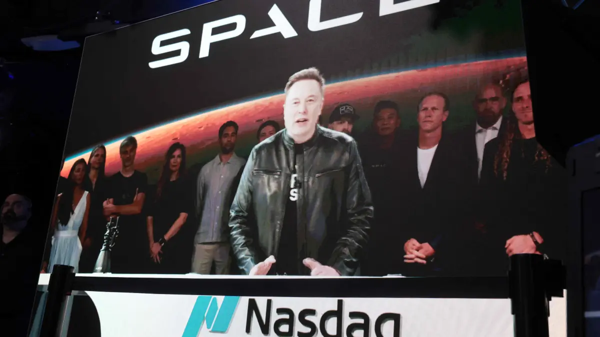 SpaceX Listed On Nasdaq Exchange: NEW YORK, NEW YORK - JUNE 12: SpaceX founder and CEO Elon Musk speaks via video at the Nasdaq Marketsite in Times Square during the launch of the SpaceX initial public offering (IPO) on the Nasdaq on June 12, 2026, in New York City. SpaceX, a rocket-making company, began trading Friday under the ticker SPCX following the largest initial public offering ever. Owner Elon Musk, who’s also CEO of Tesla and celebrated from a rocket launch site in Florida, is set to become the world’s first trillionaire. Spencer Platt/Getty Images/AFP (Photo by SPENCER PLATT / GETTY IMAGES NORTH AMERICA / Getty Images via AFP)
