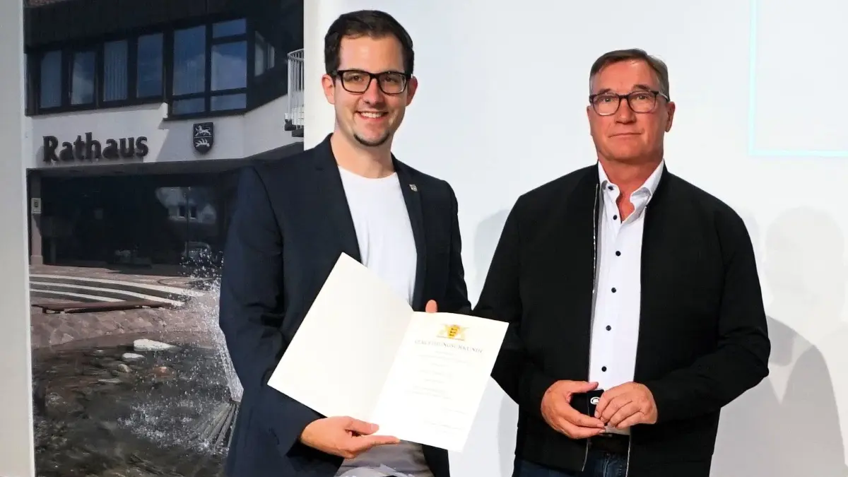 Bürgermeister Florian King (links) überreicht die Urkunde und die Landesehrennadel an Jürgen Koch