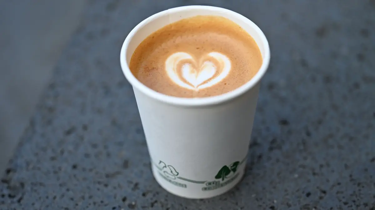 ARCHIV - 23.03.2026, Hessen, Wiesbaden: Ein Flat White mit Herz im Milchschaum ist in einen Kaffeebecher aus Pappe gefüllt. (zu dpa: «Preisgrenzen, Vorlieben, Wünsche - wie ticken Kaffeetrinker?») Foto: Michael Brandt/dpa +++ dpa-Bildfunk +++