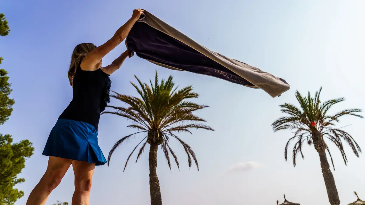 Eine Frau breitet am Strand ihr Handtuch aus: ARCHIV - 26.09.2021, Spanien, Alcudia: Extra-Geld für den Urlaub erhält nur eine Minderheit der Tarifbeschäftigten. (zu dpa: «Großes Gefälle: Nur knapp die Hälfte bekommt Urlaubsgeld») Foto: Andreas Arnold/dpa/dpa-tmn +++ dpa-Bildfunk +++