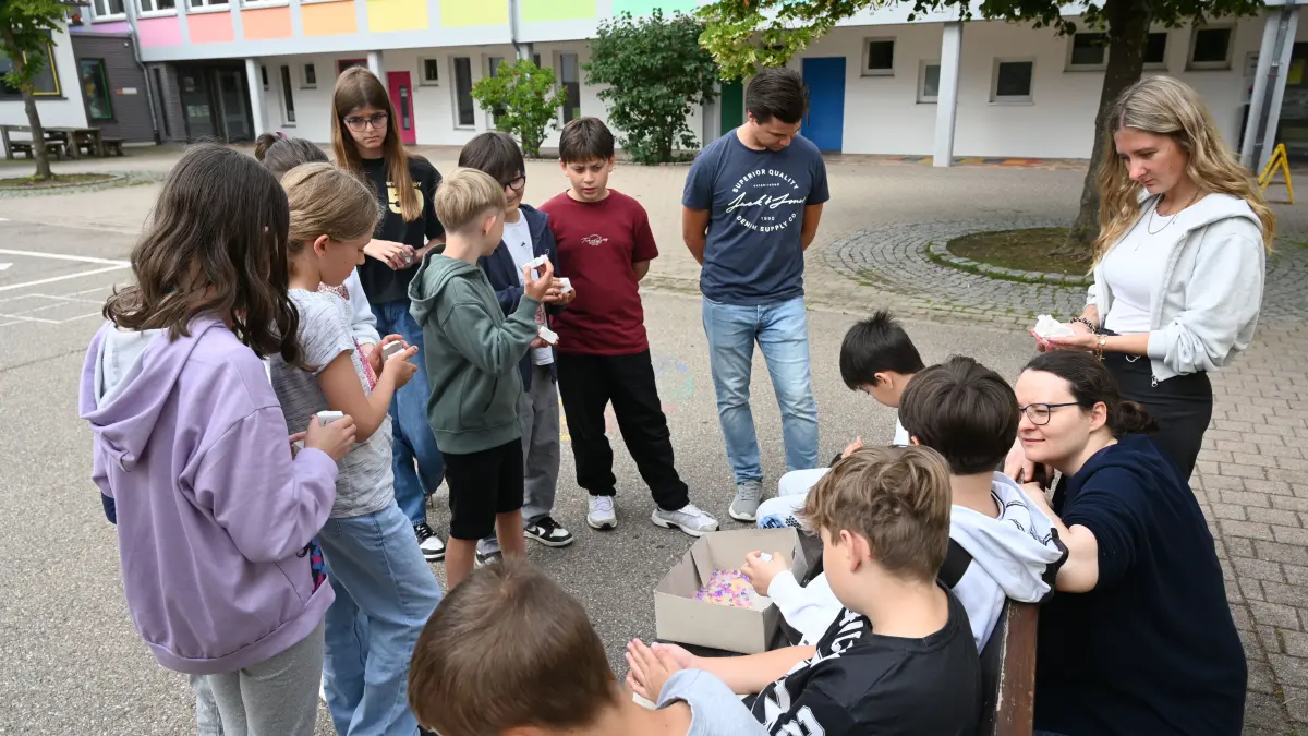 Vanessa Rodemich und Chiara Wagner besprechen mit den Kindern warum die UV-Perlen die Farbe wechselt.