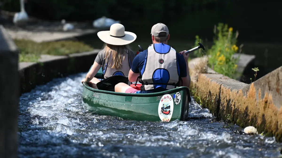 Paddeln in Gießen: ARCHIV - 09.07.2023, Hessen, Gießen: Ein Pärchen steuert bei einem Ausflug auf dem Wasser ein Kanu durch eine Bootsgasse an einem Wehr der Lahn. (zu dpa: «Fünf Freizeittipps in Hessen für heiße Sommertage») Foto: Arne Dedert/dpa +++ dpa-Bildfunk +++