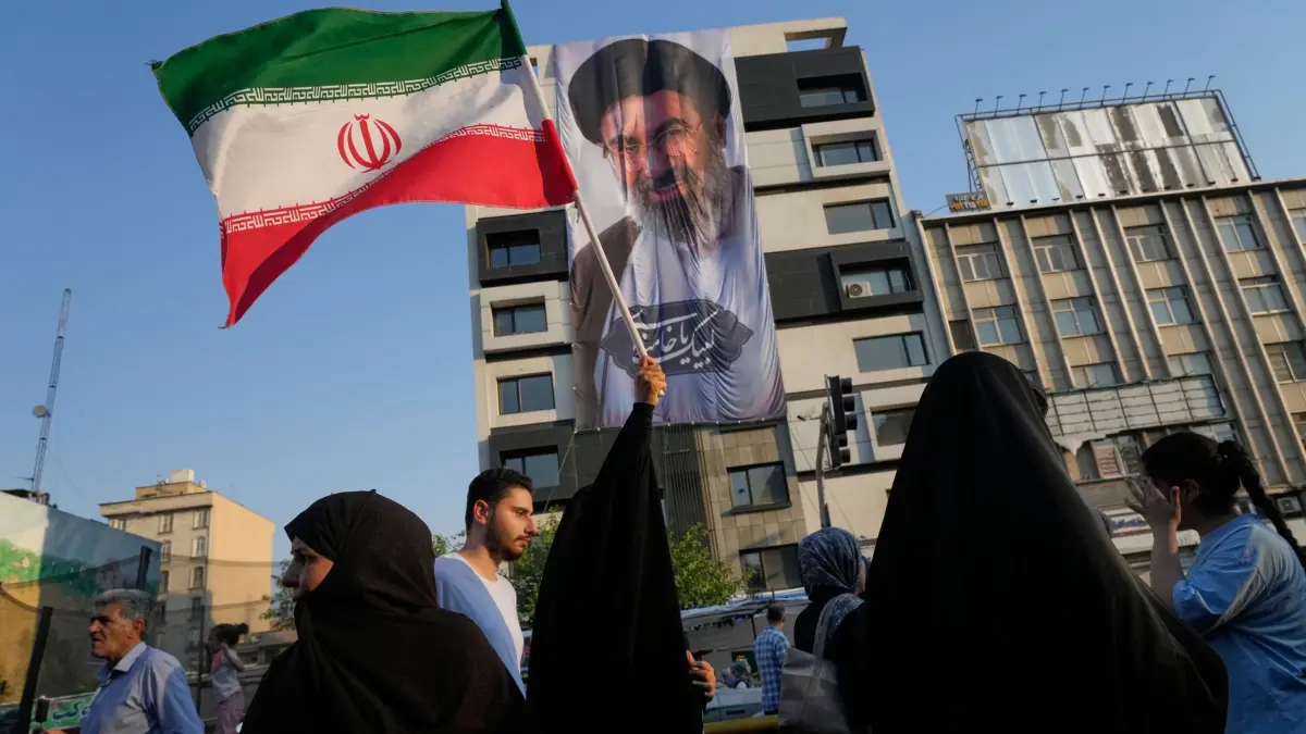 Iran-Krieg: ARCHIV - 04.06.2026, Iran, Teheran: Eine Frau hält eine iranische Flagge vor einem Banner mit einem Porträt des Obersten Führers Ayatollah Mojtaba Khamenei während eines Straßenfestes zum muslimisch-schiitischen Feiertag Eid al-Ghadir, dem Jahrestag, an dem der Prophet Mohammed seinen Nachfolger Ali ernannte, der als erster schiitischer Imam verehrt wird. (zu dpa: «Was steht im Iran-Rahmenabkommen?») Foto: Vahid Salemi/AP/dpa +++ dpa-Bildfunk +++