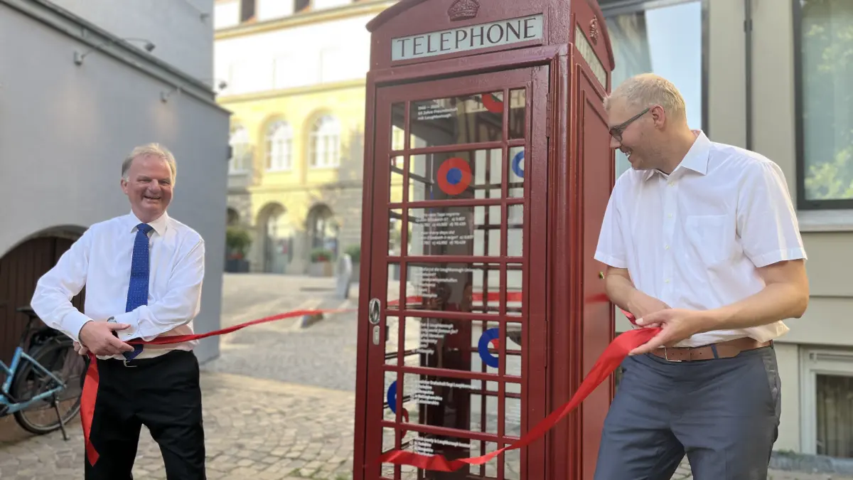 Richard East, Vorsitzender Family Exchange Group, und Haller Oberbürgermeister Daniel Bullinger weihen Telefonzelle neu ein