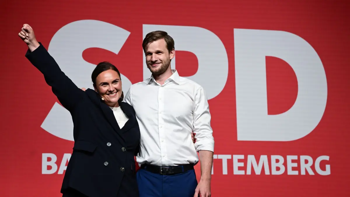 Landesparteitag der SPD Baden-Württemberg: 19.06.2026, Baden-Württemberg, Ulm: Isabel Cademartori (l) und Robin Mesarosch (l) stehen in der Donauhalle beim Landesparteitag der SPD Baden-Württemberg nach ihrer Wahl zu den neuen Landesvorsitzenden als Doppelspitze auf der Bühne. Foto: Bernd Weißbrod/dpa +++ dpa-Bildfunk +++