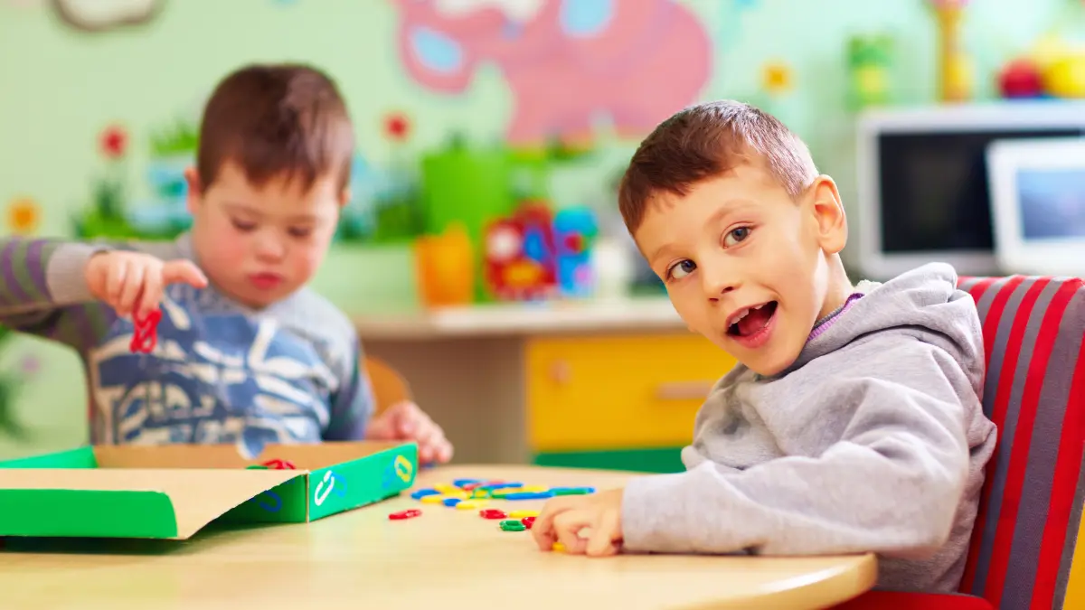 Kind Kinder Behinderung Förderung Betreuung Rollstuhl SBBZ-Ferienbetreuung Sonderpädagogik Förderschule cute kids with special needs playing with developing toys while sitting at the desk in daycare center
