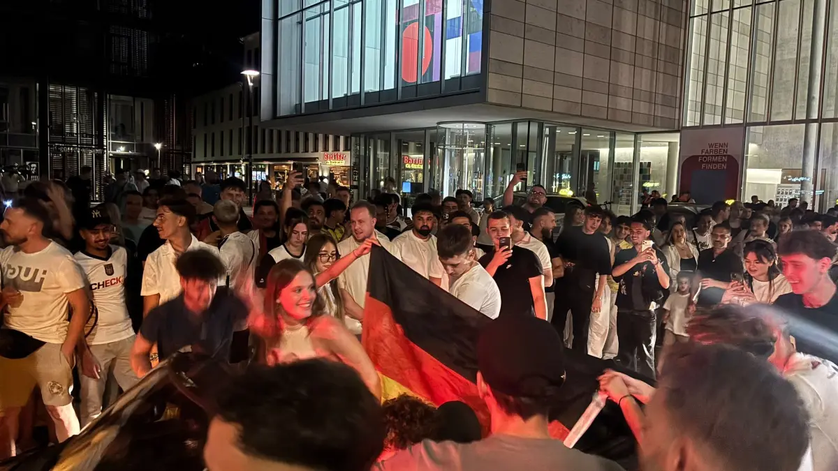 In der Neuen Mitte wird ausgelassen gefeiert, gehupt und mit Fahnen geweht.