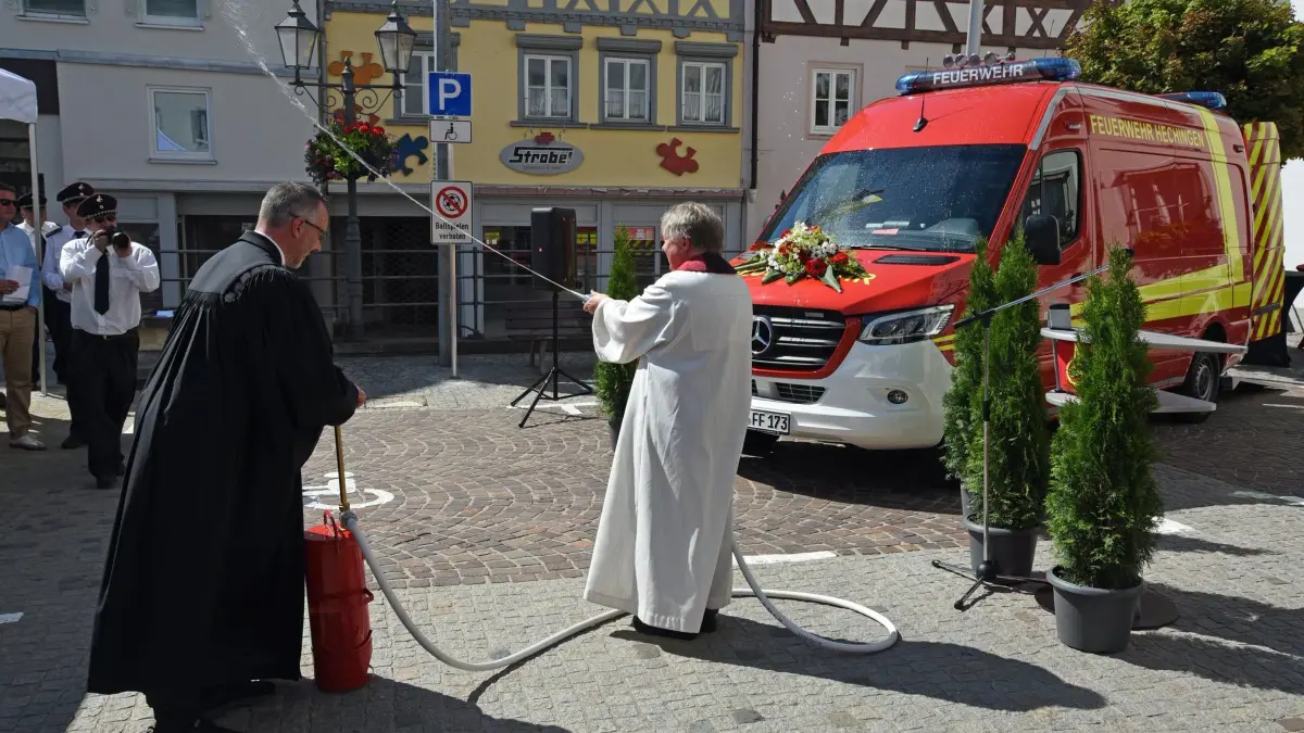 Fahrzeugweihe vor dem Hechinger Rathaus: Der evangelische Pfarrer Marcus Kalkofen bedient die Handdruckspritze, sein katholischer Kollege verteilt das Weihwasser.
