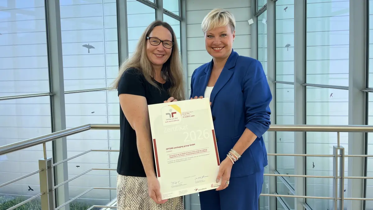Projektleiterin Andrea Herzog und Personalleiterin Katja Schrafft freuen sich über die neue Urkunde. Die gelbe Schleife am Logo bezeugt, dass Optima bereits seit zehn Jahren erfolgreich zertifiziert ist.