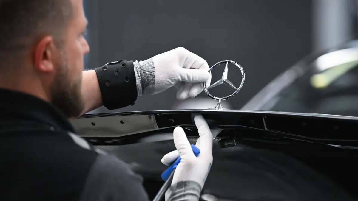 Mercedes-Benz Factory 56: ARCHIV - 30.04.2026, Baden-Württemberg, Sindelfingen: Ein Mercedes-Benz Arbeiter montiert im Mercedes-Benz Werk Sindelfingen in der Factory 56 einen Mercedes Stern auf ein Fahrzeug der S-Klasse. (zu dpa: «Mercedes verschärft Sparkurs – Sonderzahlung wird verschoben») Foto: Bernd Weißbrod/dpa +++ dpa-Bildfunk +++