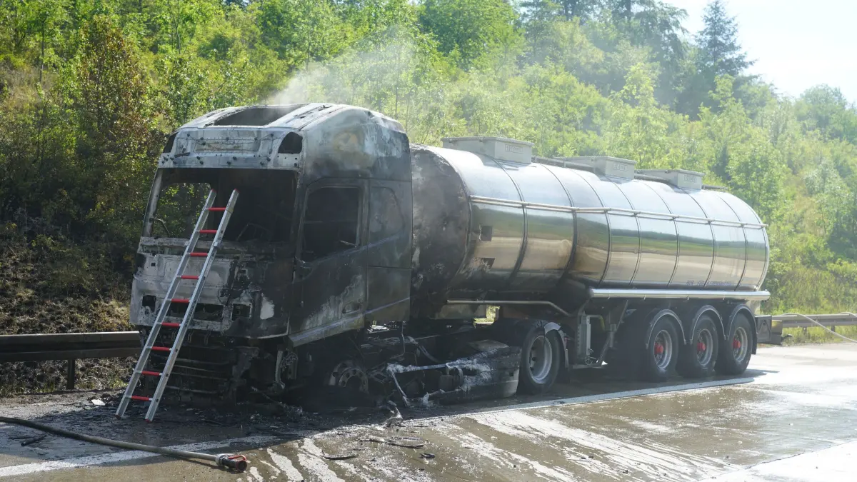 Aichelberg A8: 96 Einsatzkraefte kaempfen gegen Flammeninferno auf der A8 – Tanklastzug brennt vollstaendig aus, Rauchwolke kilometerweit sichtbar: Ein Grossbrand hat am Freitagmorgen fuer einen stundenlangen Feuerwehreinsatz und massive Verkehrsbehinderungen auf der A8 gesorgt. Gegen 9.13 Uhr wurde die Feuerwehr Gruibingen auf die Autobahn zwischen Gruibingen und Aichelberg alarmiert. Dort stand ein Tanklastzug bereits beim Eintreffen der ersten Einsatzkraefte in voller Ausdehnung in Flammen.<br />
<br />
Schon nach wenigen Minuten war klar, dass es sich um einen Grosseinsatz handeln wuerde. Das Feuer hatte bereits auf die angrenzende Boeschung uebergegriffen und breitete sich aufgrund der starken Hitze weiter aus. Aufgrund der dynamischen Einsatzlage wurden umgehend zahlreiche weitere Feuerwehren und Einsatzkraefte nachalarmiert. Die weithin sichtbare Rauchwolke war kilometerweit zu erkennen und sogar im benachbarten Landkreis deutlich sichtbar.<br />
<br />
Insgesamt waren 96 Einsatzkraefte mit 20 Fahrzeugen im Einsatz. Unterstuetzt wurden die Feuerwehren aus dem Landkreis Goeppingen von Kraeften aus dem benachbarten Landkreis Esslingen. Die Zusammenarbeit ueber die Landkreisgrenzen hinweg funktionierte reibungslos und zeigte erneut, wie wichtig die enge Abstimmung der Einsatzkraefte bei Grossschadenslagen ist.<br />
<br />
Der Tanklastzug, eine polnische Zugmaschine, war mit 25.000 Litern Speiseoel beladen. Der Fahrer wurde vorsorglich vom Rettungsdienst untersucht und medizinisch betreut. Nach ersten Erkenntnissen blieb er unverletzt.<br />
<br />
Da zunaechst unklar war, welcher Stoff sich im Tank befand, wurde vorsorglich die Werkfeuerwehr Zeller + Gmelin alarmiert. Damit sollte ausgeschlossen werden, dass sich gefaehrliche Stoffe oder Chemikalien an Bord befinden und bei Bedarf sofort Spezialmassnahmen eingeleitet werden koennen.<br />
<br />
Zur Bekaempfung des Boeschungsbrandes setzte die Feuerwehr Weilheim spezielle Loeschrucksaecke ein. Gleichzeitig wurde ein Pendelverkehr mit Feuerwehrfahrzeugen eingerichtet, um die Einsatzstelle dauerhaft mit Loeschwasser zu versorgen.<br />
<br />
An den umfangreichen Loescharbeiten beteiligt waren die Feuerwehren Gruibingen, Aichelberg, Bad Boll, Bad Ditzenbach, Wiesensteig, Ebersbach, Weilheim an der Teck und Kirchheim unter Teck sowie die Werkfeuerwehr Zeller + Gmelin. Ebenfalls vor Ort waren der Kreisbrandmeister, die Autobahnmeisterei sowie das Forstamt, die den Einsatz unterstuetzten und die notwendigen Massnahmen in ihren jeweiligen Zustaendigkeitsbereichen koordinierten.<br />
<br />
Fuer die umfangreichen Loescharbeiten musste die A8 zeitweise in beide Fahrtrichtungen vollstaendig gesperrt werden. Nachdem der Brand unter Kontrolle gebracht worden war, konnte die Gegenfahrbahn wieder fuer den Verkehr freigegeben werden. In Fahrtrichtung Stuttgart besteht die Sperrung derzeit weiterhin. Dort wird aktuell eine Fahrspur geoeffnet, um den Verkehr langsam abfliessen zu lassen. Zeitweise bildete sich ein Rueckstau von bis zu 15 Kilometern.<br />
<br />
Die hochsommerlichen Temperaturen von rund 34 Grad stellten die Einsatzkraefte zusaetzlich vor enorme Herausforderungen. Besonders Feuerwehrleute unter Atemschutz waren einer extremen koerperlichen Belastung ausgesetzt. Um die im Stau wartenden Verkehrsteilnehmer zu unterstuetzen, verteilte die Feuerwehr Wiesensteig Trinkwasser an die Autofahrer.<br />
<br />
Der ausgebrannte Tanklastzug soll im weiteren Verlauf auf einen Parkplatz gebracht werden. Dort wird die Ladung in ein anderes Fahrzeug umgepumpt, damit die Bergungsarbeiten den Verkehr auf der Autobahn nicht laenger als notwendig beeintraechtigen. Nach derzeitiger Einschaetzung werden die Arbeiten noch mehrere Stunden andauern.<br />
<br />
Wie es zu dem Brand kommen konnte, ist derzeit noch unklar. Die Polizei hat die Ermittlungen zur Brandursache aufgenommen. Auch die Hoehe des entstandenen Sachschadens ist bislang nicht bekannt und wird derzeit ermittelt.<br />
<br />
Bereits am Montag hatte es auf demselben Streckenabschnitt einen groesseren Feuerwehreinsatz mit einem Lastwagen gegeben. Der Brand am Freitag ist damit bereits der zweite groessere Lkw-Grosseinsatz innerhalb einer Woche auf diesem Abschnitt der A8.