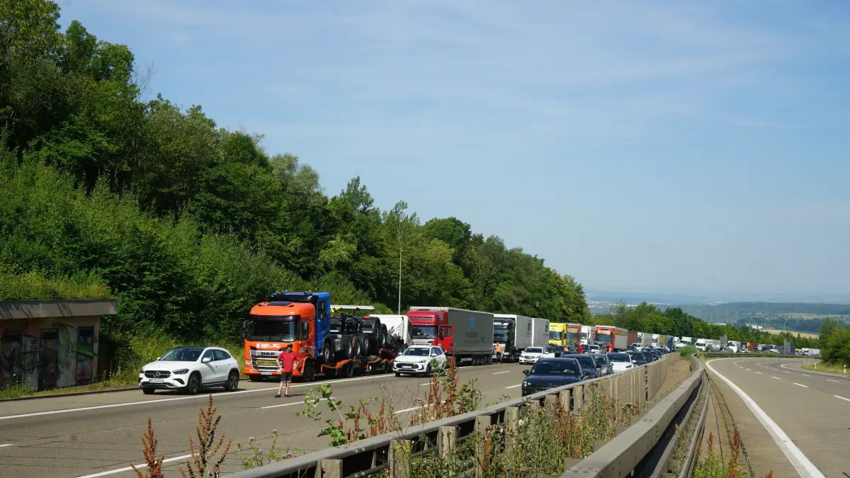 Aichelberg A8: 96 Einsatzkraefte kaempfen gegen Flammeninferno auf der A8 – Tanklastzug brennt vollstaendig aus, Rauchwolke kilometerweit sichtbar: Ein Grossbrand hat am Freitagmorgen fuer einen stundenlangen Feuerwehreinsatz und massive Verkehrsbehinderungen auf der A8 gesorgt. Gegen 9.13 Uhr wurde die Feuerwehr Gruibingen auf die Autobahn zwischen Gruibingen und Aichelberg alarmiert. Dort stand ein Tanklastzug bereits beim Eintreffen der ersten Einsatzkraefte in voller Ausdehnung in Flammen.<br />
<br />
Schon nach wenigen Minuten war klar, dass es sich um einen Grosseinsatz handeln wuerde. Das Feuer hatte bereits auf die angrenzende Boeschung uebergegriffen und breitete sich aufgrund der starken Hitze weiter aus. Aufgrund der dynamischen Einsatzlage wurden umgehend zahlreiche weitere Feuerwehren und Einsatzkraefte nachalarmiert. Die weithin sichtbare Rauchwolke war kilometerweit zu erkennen und sogar im benachbarten Landkreis deutlich sichtbar.<br />
<br />
Insgesamt waren 96 Einsatzkraefte mit 20 Fahrzeugen im Einsatz. Unterstuetzt wurden die Feuerwehren aus dem Landkreis Goeppingen von Kraeften aus dem benachbarten Landkreis Esslingen. Die Zusammenarbeit ueber die Landkreisgrenzen hinweg funktionierte reibungslos und zeigte erneut, wie wichtig die enge Abstimmung der Einsatzkraefte bei Grossschadenslagen ist.<br />
<br />
Der Tanklastzug, eine polnische Zugmaschine, war mit 25.000 Litern Speiseoel beladen. Der Fahrer wurde vorsorglich vom Rettungsdienst untersucht und medizinisch betreut. Nach ersten Erkenntnissen blieb er unverletzt.<br />
<br />
Da zunaechst unklar war, welcher Stoff sich im Tank befand, wurde vorsorglich die Werkfeuerwehr Zeller + Gmelin alarmiert. Damit sollte ausgeschlossen werden, dass sich gefaehrliche Stoffe oder Chemikalien an Bord befinden und bei Bedarf sofort Spezialmassnahmen eingeleitet werden koennen.<br />
<br />
Zur Bekaempfung des Boeschungsbrandes setzte die Feuerwehr Weilheim spezielle Loeschrucksaecke ein. Gleichzeitig wurde ein Pendelverkehr mit Feuerwehrfahrzeugen eingerichtet, um die Einsatzstelle dauerhaft mit Loeschwasser zu versorgen.<br />
<br />
An den umfangreichen Loescharbeiten beteiligt waren die Feuerwehren Gruibingen, Aichelberg, Bad Boll, Bad Ditzenbach, Wiesensteig, Ebersbach, Weilheim an der Teck und Kirchheim unter Teck sowie die Werkfeuerwehr Zeller + Gmelin. Ebenfalls vor Ort waren der Kreisbrandmeister, die Autobahnmeisterei sowie das Forstamt, die den Einsatz unterstuetzten und die notwendigen Massnahmen in ihren jeweiligen Zustaendigkeitsbereichen koordinierten.<br />
<br />
Fuer die umfangreichen Loescharbeiten musste die A8 zeitweise in beide Fahrtrichtungen vollstaendig gesperrt werden. Nachdem der Brand unter Kontrolle gebracht worden war, konnte die Gegenfahrbahn wieder fuer den Verkehr freigegeben werden. In Fahrtrichtung Stuttgart besteht die Sperrung derzeit weiterhin. Dort wird aktuell eine Fahrspur geoeffnet, um den Verkehr langsam abfliessen zu lassen. Zeitweise bildete sich ein Rueckstau von bis zu 15 Kilometern.<br />
<br />
Die hochsommerlichen Temperaturen von rund 34 Grad stellten die Einsatzkraefte zusaetzlich vor enorme Herausforderungen. Besonders Feuerwehrleute unter Atemschutz waren einer extremen koerperlichen Belastung ausgesetzt. Um die im Stau wartenden Verkehrsteilnehmer zu unterstuetzen, verteilte die Feuerwehr Wiesensteig Trinkwasser an die Autofahrer.<br />
<br />
Der ausgebrannte Tanklastzug soll im weiteren Verlauf auf einen Parkplatz gebracht werden. Dort wird die Ladung in ein anderes Fahrzeug umgepumpt, damit die Bergungsarbeiten den Verkehr auf der Autobahn nicht laenger als notwendig beeintraechtigen. Nach derzeitiger Einschaetzung werden die Arbeiten noch mehrere Stunden andauern.<br />
<br />
Wie es zu dem Brand kommen konnte, ist derzeit noch unklar. Die Polizei hat die Ermittlungen zur Brandursache aufgenommen. Auch die Hoehe des entstandenen Sachschadens ist bislang nicht bekannt und wird derzeit ermittelt.<br />
<br />
Bereits am Montag hatte es auf demselben Streckenabschnitt einen groesseren Feuerwehreinsatz mit einem Lastwagen gegeben. Der Brand am Freitag ist damit bereits der zweite groessere Lkw-Grosseinsatz innerhalb einer Woche auf diesem Abschnitt der A8.