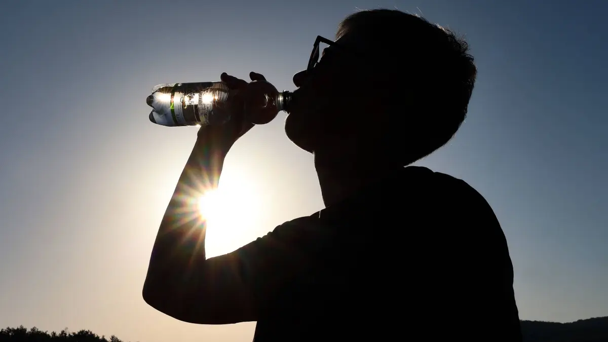 Sommer im Siegerland: Sommer im Siegerland. Es ist sehr heiss heiß und die Temperaturen sollen weiter ansteigen. Der Himmel ist blau und die Sonne strahlt vom wolkenlosen Himmel. Im Vordergrund trinkt eine Frau am Morgen Wasser aus einer Flasche. Sommer am 26.06.2026 in Siegen/Deutschland. *** Summer in the Siegerland. It is very hot, and temperatures are expected to rise further. The sky is blue, and the sun is shining from a cloudless sky. In the foreground, a woman is drinking water from a bottle in the morning. Summer on June 26, 2026, in Siegen, Germany.