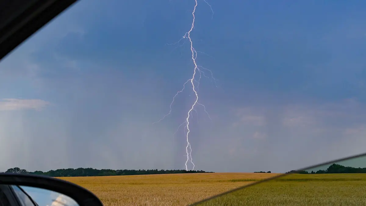 Hitze in Deutschland - Gewitter in Brandenburg: 28.06.2026, Brandenburg, Sieversdorf: Blick aus einem Auto auf einen Blitz vor dunklen Gewitterwolken über der Landschaft im östlichen Brandenburg. Foto: Patrick Pleul/dpa +++ dpa-Bildfunk +++