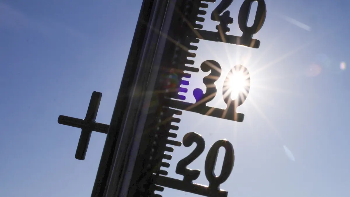 Die Sonne scheint hinter einem Thermometer (Illustration). (zu dpa: «Hitze: Was Nord- von Südeuropäern lernen können») +++ dpa-Bildfunk +++