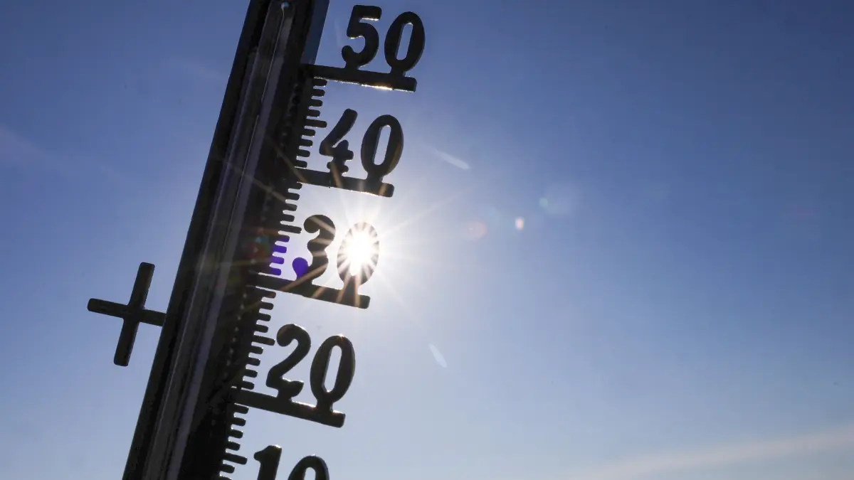 Die Sonne scheint hinter einem Thermometer (Illustration). (zu dpa: «Hitze: Was Nord- von Südeuropäern lernen können») +++ dpa-Bildfunk +++