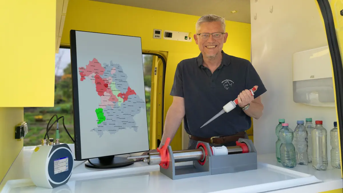 Matthias Ahlbrecht untersucht eine Brunnenwasserprobe; mit Nitratkarte von Bayern im Labormobil vom VSR-Gewässerschutz