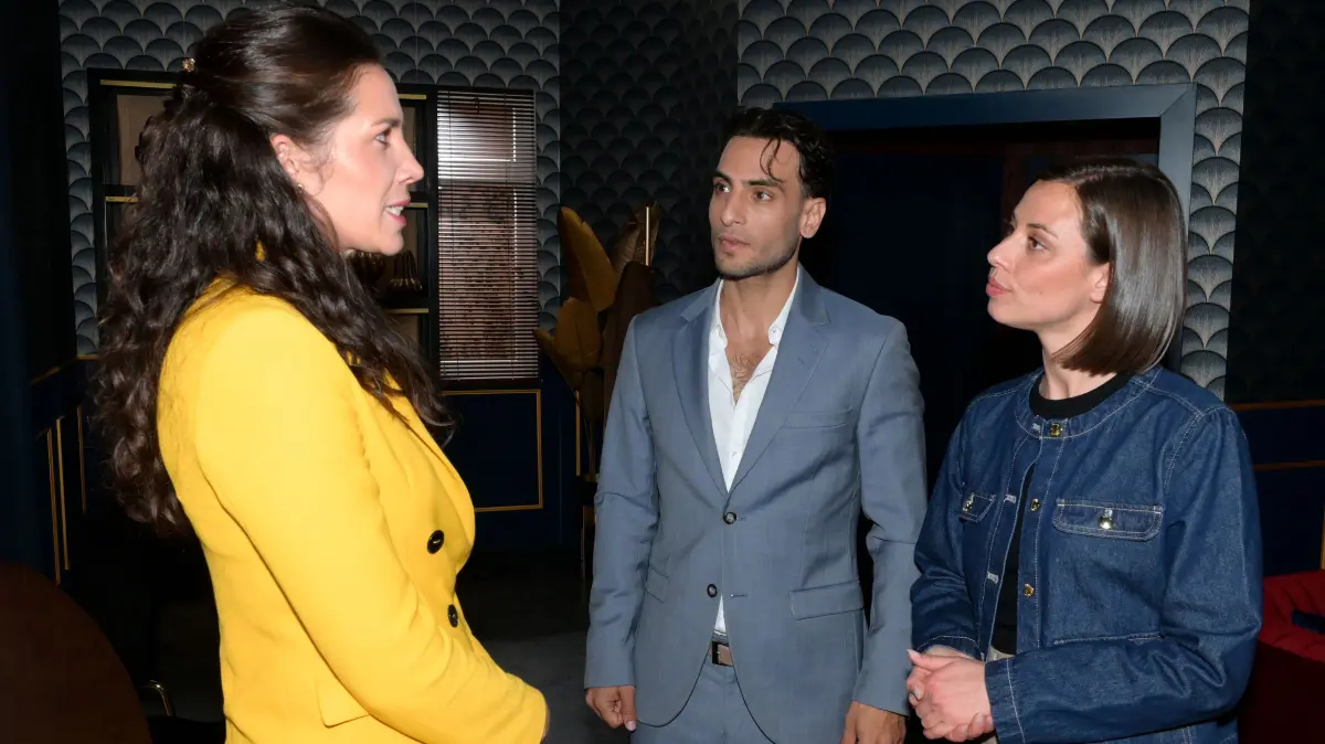 Bei dem wichtigen Gespräch mit Frau Larios (Theresa Tripp, l.) müssen Nihat (Timur Ülker) und Matilda (Anna-Katharina Fecher) wieder das verliebte Pärchen spielen.