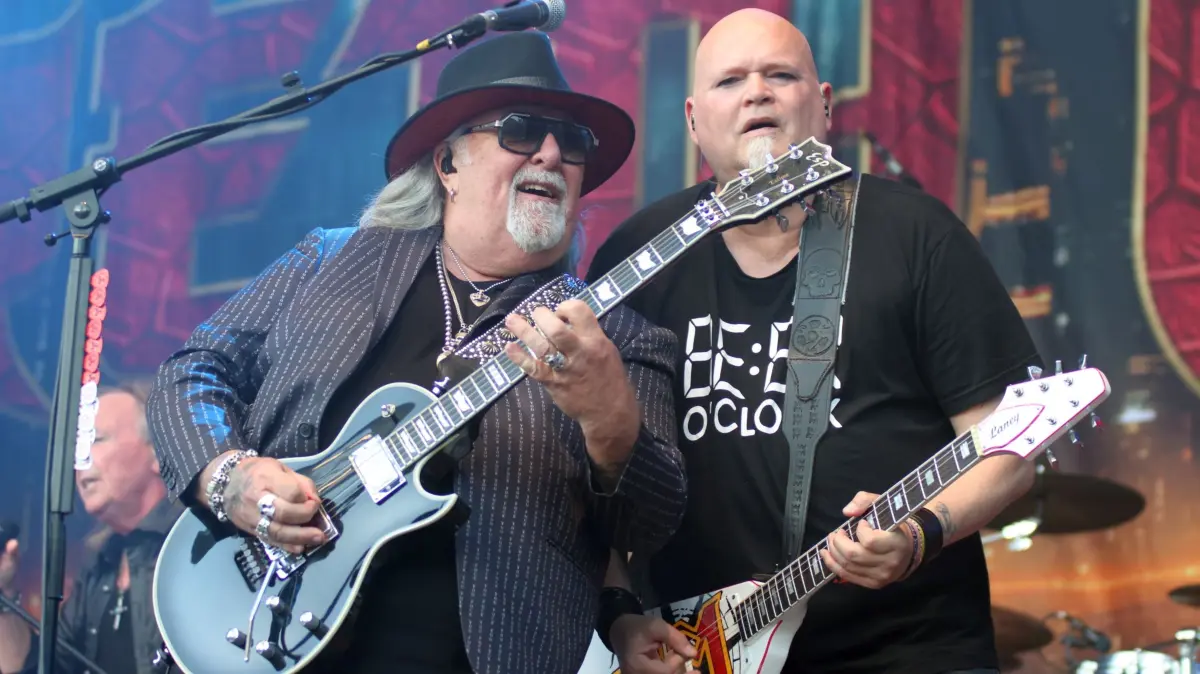 Zwei Gitarren, zwei Männer, ein gemeinsamer Gedanke: dass man Songs auch tragen kann, ohne sie zu erdrücken. Ken Hammer und Chris Laney spielen, als würden sie sich seit Jahrzehnten kennen – tun sie ja auch. Kein Wettbewerb, kein Show-off, eher ein leises Einverständnis darüber, dass hier wieder einmal etwas funktioniert, das größer ist als einzelne Riffs.