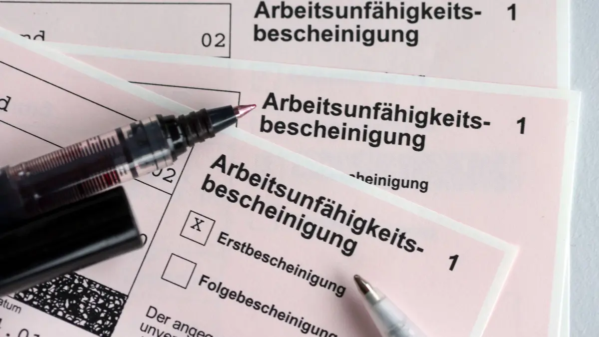 Krankenschein für Arbeitnehmer: ARCHIV - 14.01.2022, Schleswig-Holstein, Kiel: Stifte liegen auf den Arbeitsunfähigkeitsbescheinigungen für Arbeitnehmer im Falle einer Krankschreibung durch den Arzt. (zu dpa: «Weniger Fehltage in Sachsen – Arbeitgeber gefragt») Foto: Jens Büttner/dpa-Zentralbild/dpa +++ dpa-Bildfunk +++