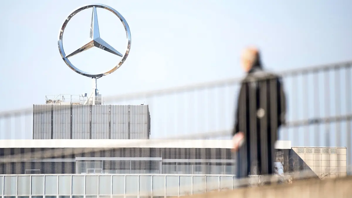 ARCHIV - 18.03.2020, Baden-Württemberg, Stuttgart: Ein Mitarbeiter von Daimler geht am Mercedes-Benz Werk Untertürkheim zum Schichtwechsel vor einem Mercedes-Stern Richtung Werk. (zu dpa: «Autobauer Daimler streicht deutlich mehr Stellen als gedacht») Foto: Sebastian Gollnow/dpa +++ dpa-Bildfunk +++