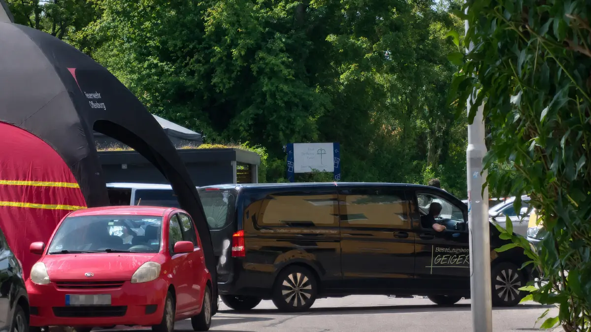 Der Leichenwagen fährt von Tatort weg.