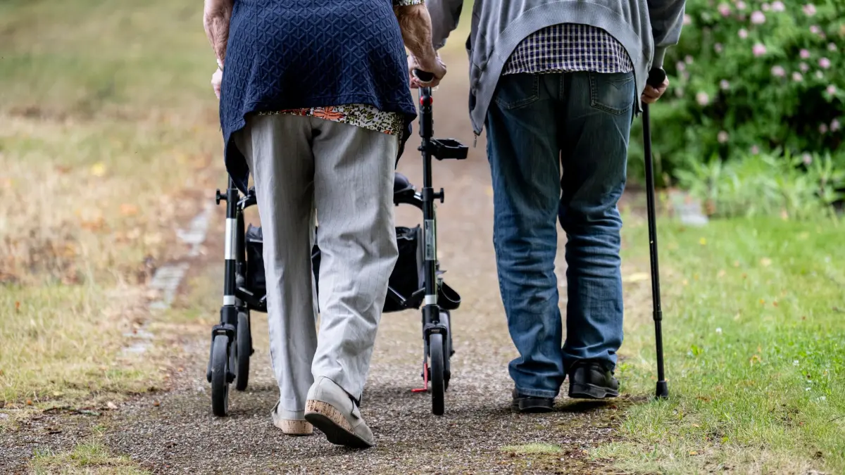 Lebenserwartung in Thüringen gestiegen: ARCHIV - 09.07.2025, Brandenburg, Potsdam: Zwei Senioren gehen mit Gehhilfen durch den Garten eines Seniorenheims. Eine Person nutzt einen Rollator, die andere einen Gehstock. (zu dpa: «Darum leben Thüringer immer länger») Foto: Fabian Sommer/dpa +++ dpa-Bildfunk +++