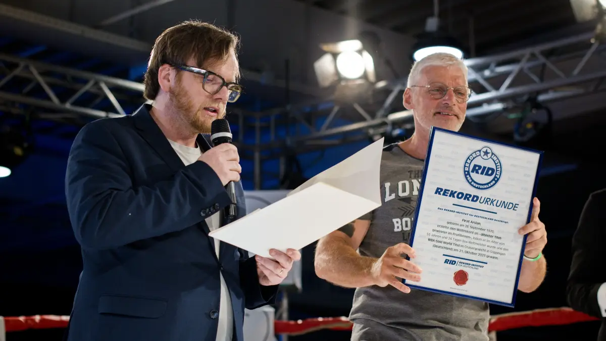 Der Verleger Dr. Matthias Slunitschek aus Schwäbisch Hall Steinbach hält die Laudatio für Firat Arslan, der als ältester Boxer einen internationalen Titelkampf bestritten hat. Auf dem Foto mit Peter Frohn-Lux, Weltrekordhalter im Masterboxen. Er hat dann die Urkunde übergeben.