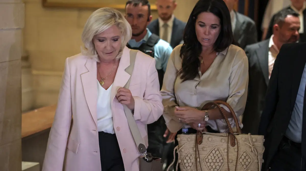 FRANCE-POLITICS-JUSTICE-TRIAL-RN: President of Rassemblement National parliamentary group Marine Le Pen (L) flanked by Member of the European Parliament Catherine Griset (R) leave after the verdict in the appeal trial of RN former or actual members on charges of embezzlement of European public funds in a case of alleged European Parliament fake jobs at Paris Court of Appeal on July 7, 2026. An appeals court on July 7, 2026, handed France's far-right chief Marine Le Pen a one-year term with an ankle tag over a fake jobs scam in the European parliament, casting doubt on whether she will run for president next April. The court also prevented her from running for office for 15 months, a ban expected to have expired this year. (Photo by Kenzo TRIBOUILLARD / AFP)