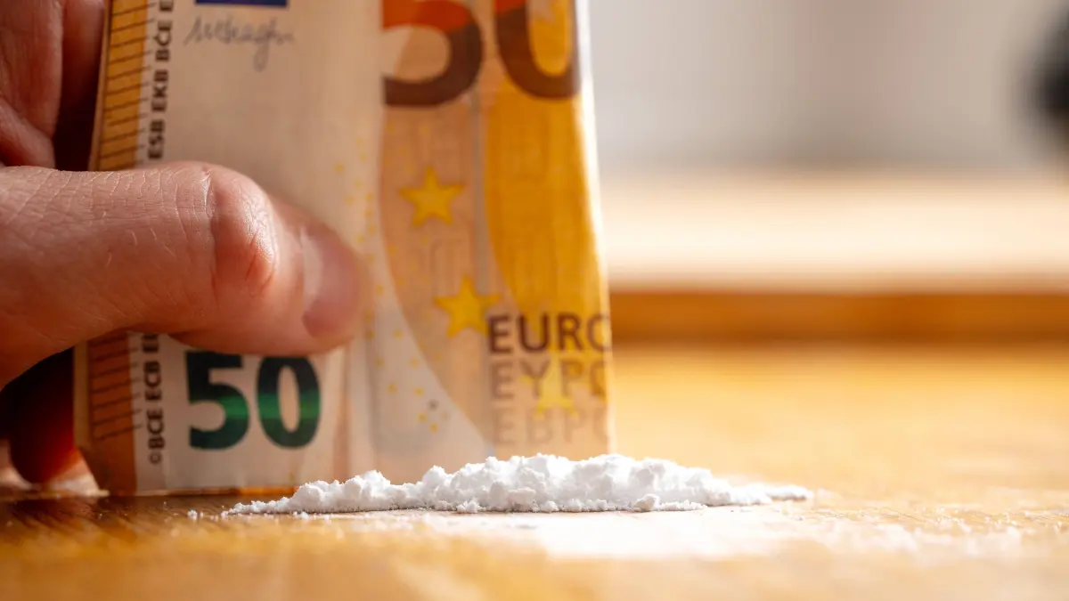 Bavaria, Germany - April 16, 2025: A rolled-up 50-euro bill lies directly next to a line of white powder - symbolic image of drug trafficking and street sale of cocaine. *** Ein zusammengerollter 50-Euro-Schein liegt direkt neben einer Linie weißem Pulver Symbolbild für Drogenhandel und Straßenverkauf von Kokain.