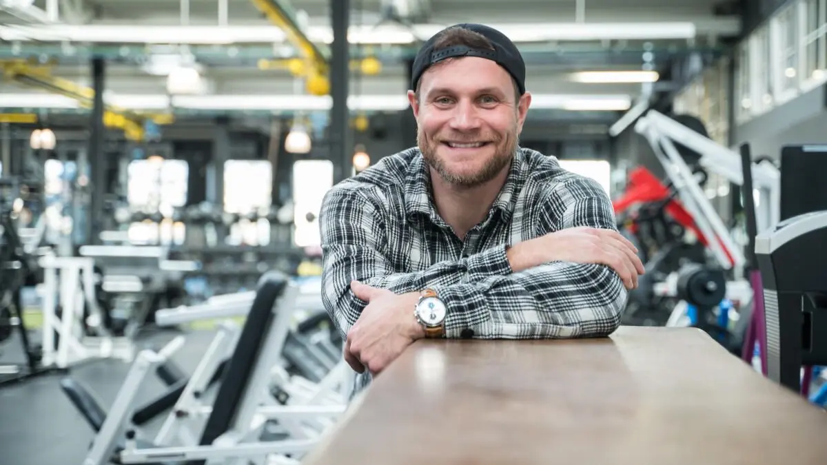 Mimi Kraus in seinem Fitness-Studio. Er gibt Hinweise auf die Nutzung der Trimm-Dih geräte.