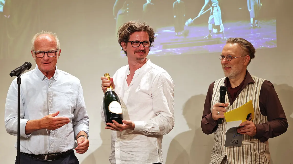 Das Publikum wählte "Mephisto" zur Aufführung der Saison 2025/2026. Regisseur Malte Kreutzfeldt freute sich auch über eine Flasche Champagner, gespendet von den Theaterfreunden (links Vorstandsmitglied Detlef Czypulovski). Chefdramaturg Christian Katzschmann (rechts) moderierte die Theaterpreis-Gala.