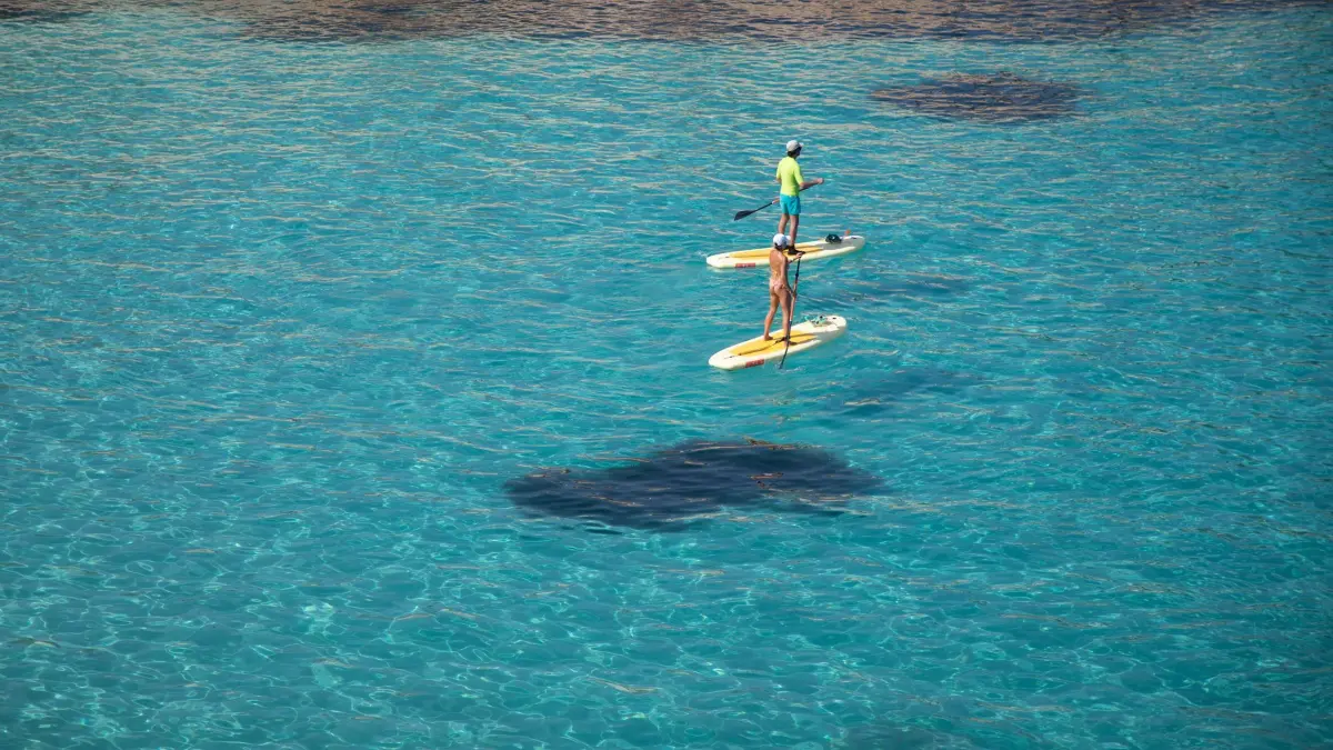 Wetter auf Mallorca: 09.07.2026, Spanien, Calvia: Mit Sup-Boards gleiten Menschen über das türkisblaue Wasser am Strand von Portals Vells. Foto: Clara Margais/dpa +++ dpa-Bildfunk +++
