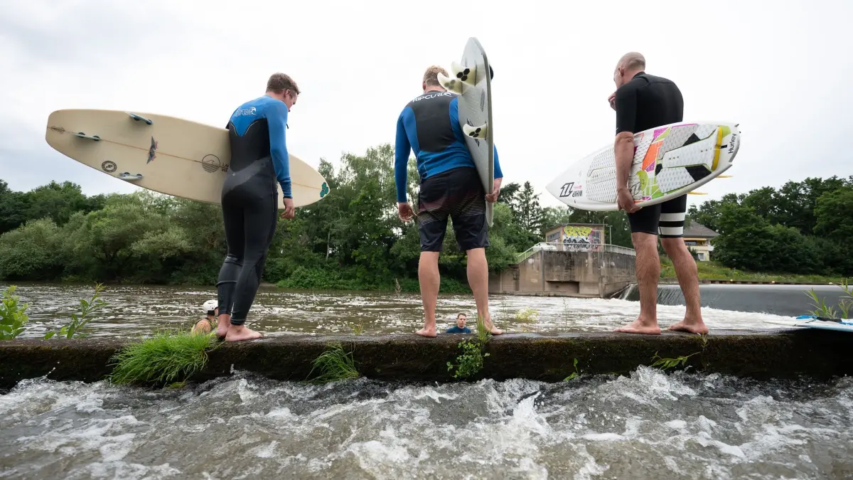 „Lahnwelle“ in Hessen: ARCHIV - 12.07.2021, Hessen, Gießen: Surfer stehen an dem Wehr, an dem die Surfwelle entstehen soll. (zu dpa: «Hessen statt Hawaii: Frankfurt könnte Surfwelle bekommen») Foto: Sebastian Gollnow/dpa +++ dpa-Bildfunk +++