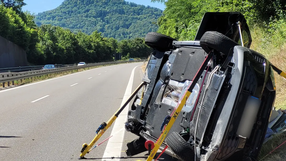 Verkehrsunfall mit Verletzten bei Hechingen: 12.07.2026, Baden-Württemberg, Hechingen: Ein zur Seite gekipptes Fahrzeug liegt auf der B27 an der Unfallstelle am Straßenrand. Im Hintergrund ist die Burg Hohenzollern zu sehen. Bei dem Unfall auf der Bundesstraße nahe Hechingen im Zollernalbkreis sind vier Menschen teils schwer verletzt worden. An dem Unfall seien zwei Fahrzeuge beteiligt gewesen. Der Fahrer des Autos, das den Unfall mutmaßlich verursacht habe, sei nach derzeitigen Erkenntnissen schwer verletzt worden, sagte ein Polizeisprecher. Foto: Ralf Biesinger/dpa +++ dpa-Bildfunk +++