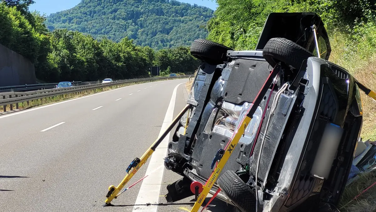 Verkehrsunfall mit Verletzten bei Hechingen: 12.07.2026, Baden-Württemberg, Hechingen: Ein zur Seite gekipptes Fahrzeug liegt auf der B27 an der Unfallstelle am Straßenrand. Im Hintergrund ist die Burg Hohenzollern zu sehen. Bei dem Unfall auf der Bundesstraße nahe Hechingen im Zollernalbkreis sind vier Menschen teils schwer verletzt worden. An dem Unfall seien zwei Fahrzeuge beteiligt gewesen. Der Fahrer des Autos, das den Unfall mutmaßlich verursacht habe, sei nach derzeitigen Erkenntnissen schwer verletzt worden, sagte ein Polizeisprecher. Foto: Ralf Biesinger/dpa +++ dpa-Bildfunk +++