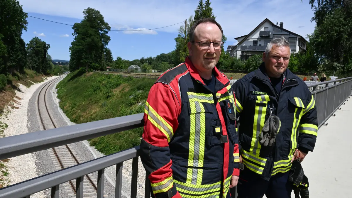 Die Feuerwehrmänner Stefan Kuc (l) und Thomas Steinhardt (r) stehen an einer Unfallstelle, an der ein Jahr zuvor ein Zug entgleist war. Sie waren bei diesem Unglück im Einsatz.