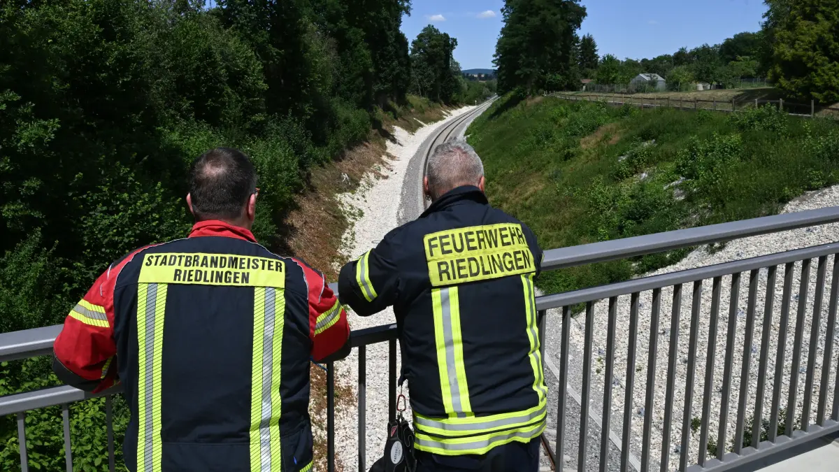 Die Feuerwehrmänner und Stefan Kuc (l) und Thomas Steinhardt (r) stehen an einer Unfallstelle, an der ein Jahr zuvor ein Zug entgleist war. Sie waren bei diesem Unglück im Einsatz.