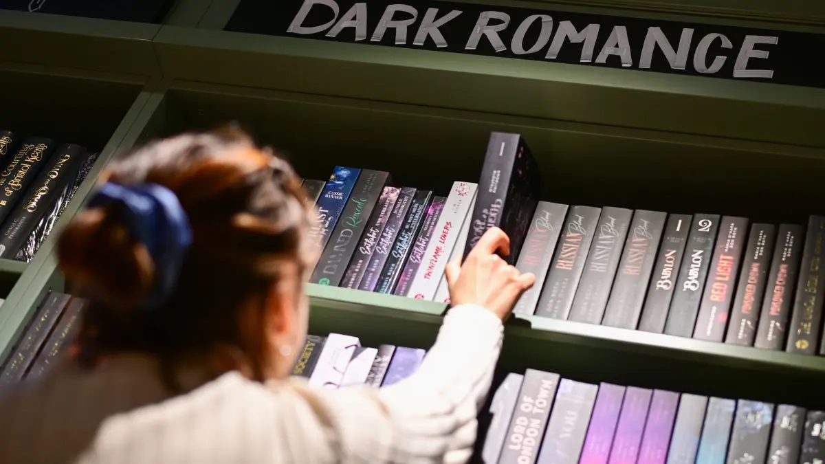 Dark Romance: ILLUSTRATION - 07.07.2026, Berlin: Eine Mitarbeiterin nimmt ein Buch im Regal des Genre "Dark Romance" in einer Thalia-Buchhandlung aus dem Regal. (gestellte Szene). Das Genre boomt und sorgt für kontroverse Diskussionen. (zu dpa: «Dark Romance: Wie ein umstrittenes Genre die Buchwelt verändert») Foto: Sebastian Gollnow/dpa +++ dpa-Bildfunk +++