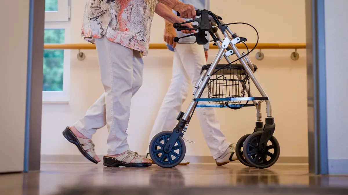 Pflegekraft mit einer älteren Dame in einem Pflegeheim